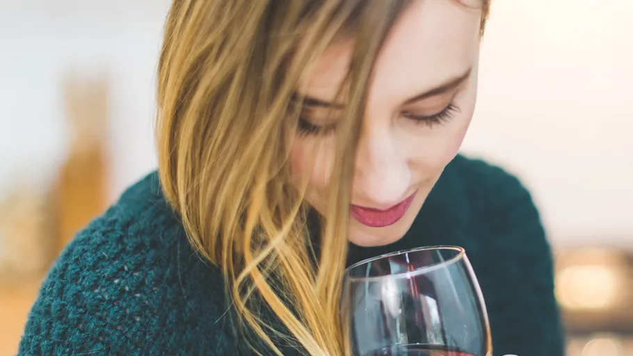 Woman smelling wine in glass indoors.