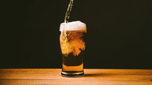 Beer poured into a glass on a table.
