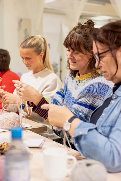 Group of women knitting together indoors.