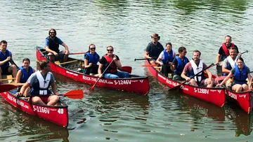 Gruppe von Menschen, die zusammen auf einem Fluss Kanu fahren.