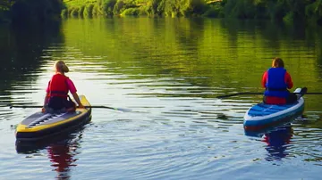 Two people kayaking on a calm river.