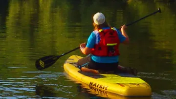 Person paddling on yellow board in water.