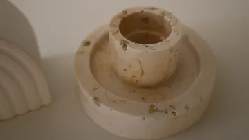 Circular marble holder with gold specks, on surface.