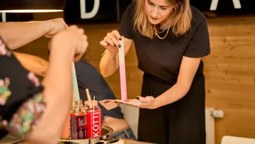 Woman examining colorful paper strips at table.
