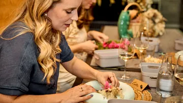 Woman arranging flowers at a table setting.