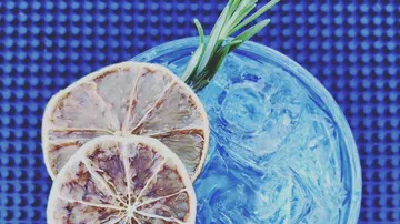 Cocktail mit Zitronenscheiben und Rosmaringarnitur.