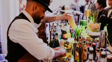 Barkeeper mixt Getränke an einer belebten Bar.