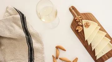 Käsescheiben und Walnüsse auf einem Brett mit Wein.