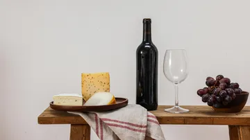 Käse, Weinflasche, Glas, Trauben auf dem Tisch.