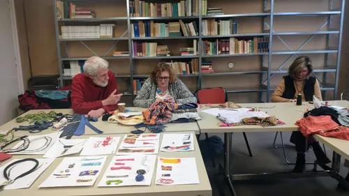 Three people working with fabric at tables in library.