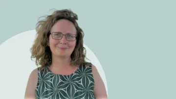 Frau lächelt, trägt eine Brille, grünes gemustertes Kleid.