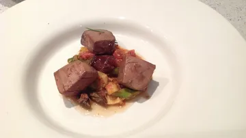 Beef cubes on vegetable medley in dish.
