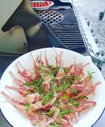 Herbed lamb chops on grill with tomatoes.