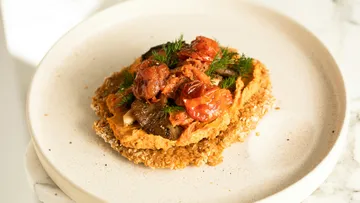 Plate with lentil cake topped with vegetables.