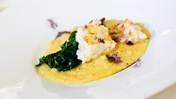 Hummer mit cremiger Polenta und Gemüse auf dem Teller.