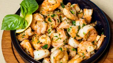 Grilled shrimp in a bowl with basil garnish.