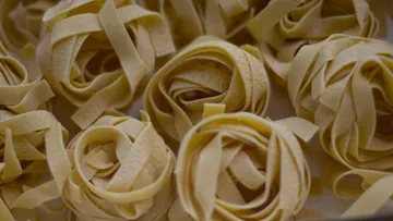 Rolled pasta nests on a surface.