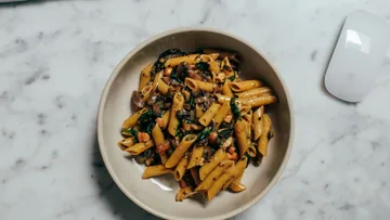 Pasta with vegetables in a bowl on table.