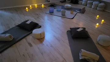 Yogamatten und Kissen mit Kerzen in einem ruhigen Raum.
