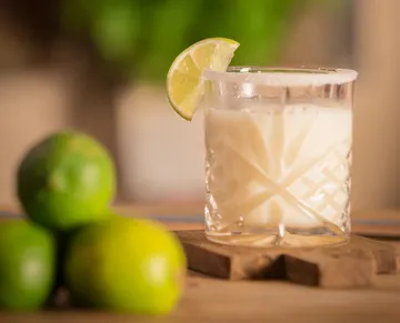 Glass of creamy drink with lime garnish.