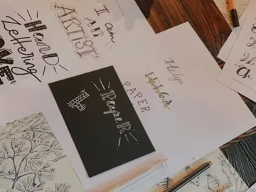 Papier mit Schriftzügen und Stiften auf einem Tisch.