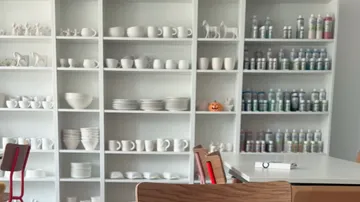Weiße Regale mit Töpferwaren und Farben, Studioumgebung.