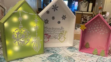 Dekorative Holzkisten mit Weihnachtsmotiven, beleuchtet und bunt.