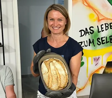 Eine lächelnde Frau hält ein goldenes Brot drinnen.