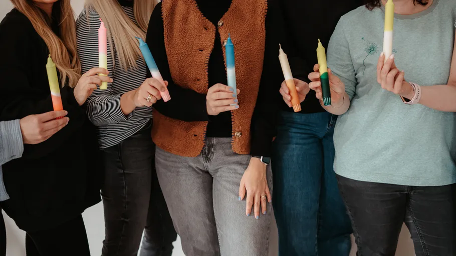 Gruppe von Menschen, die bunte Kerzen in der Hand halten.