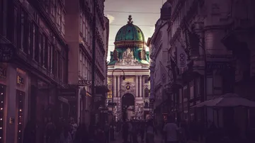 People walking on street toward domed building.