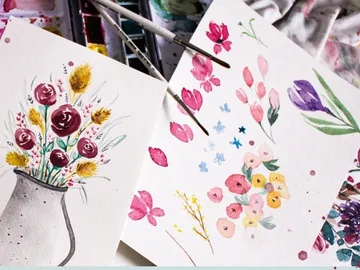 Watercolors with floral patterns on paper, in a creative environment.