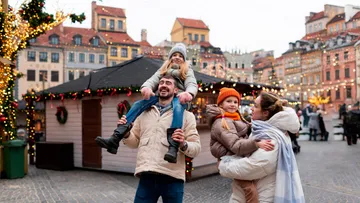 Family enjoying holiday market with lights.