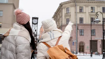 Zwei Personen in Winterkleidung zeigen auf das Gebäude.