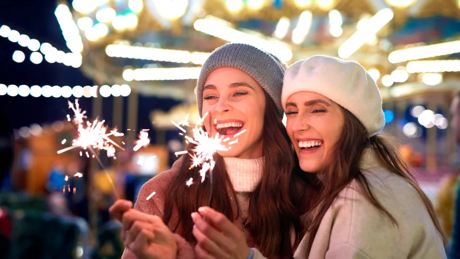 Two women holding sparklers at night carnival.