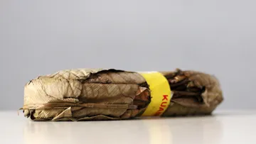 Gerolltes Tabakblattbündel auf weißer Oberfläche.