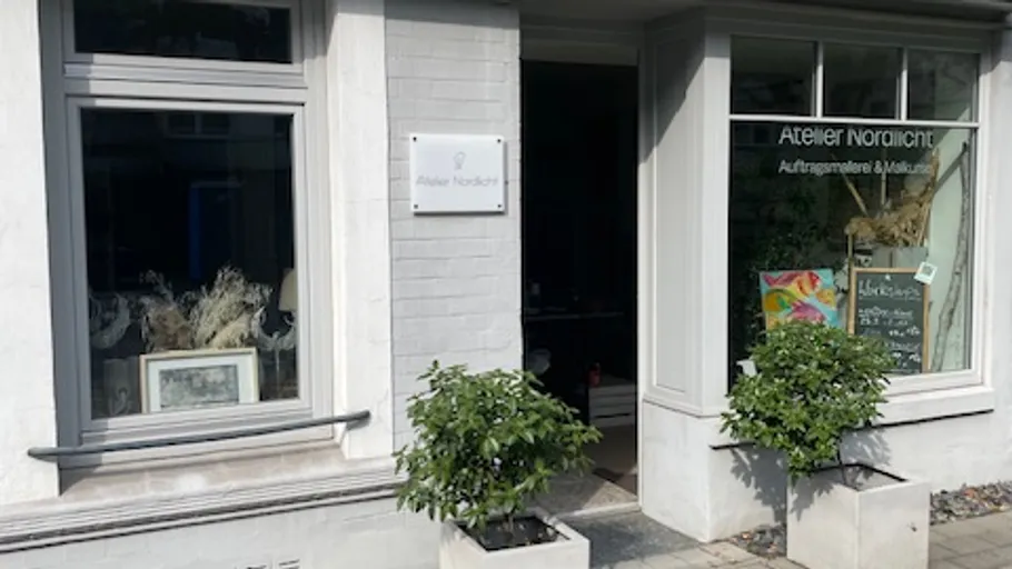 Art studio entrance with plants, sign reads 'Atelier Nordlicht.'