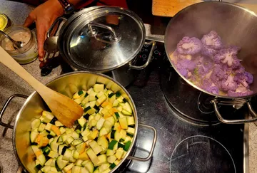 Zucchini und lila Blumenkohl auf dem Herd kochen.