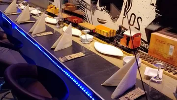 Restauranttischbestuhlung im Zugstil mit Servietten und Gläsern.
