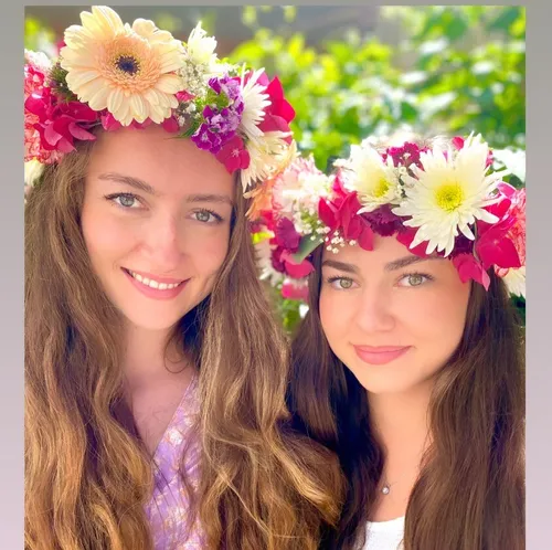 Zwei Frauen tragen Blumenkronen im Freien.