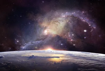 Sonnenaufgang über der Erde mit einer Spiralgalaxie darüber.