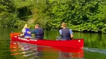 Three people canoeing on tranquil lake.