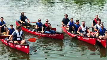 Group paddling red canoes on a river.