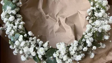 White floral wreath on crumpled brown paper.