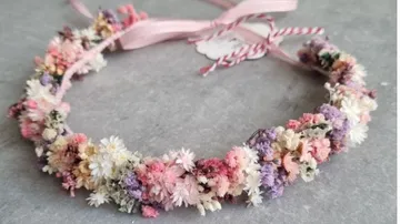 Floral crown with pastel flowers on grey surface.