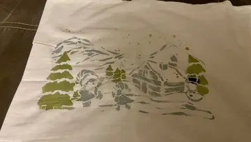 Gemütliche Winterszene mit Bäumen und Hütte auf Stoff.