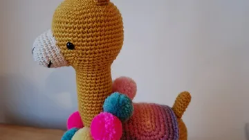 Gehäkeltes Lama-Spielzeug mit bunten Pompons.