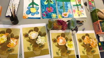 Kunsttisch mit Gemälden, Blumen und Zubehör.