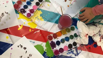 Kindermalerei mit Wasserfarben auf dem Tisch.