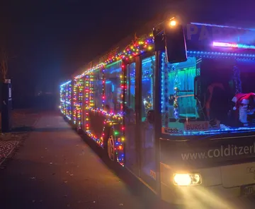 Der Bus ist nachts mit bunten Weihnachtslichtern geschmückt.