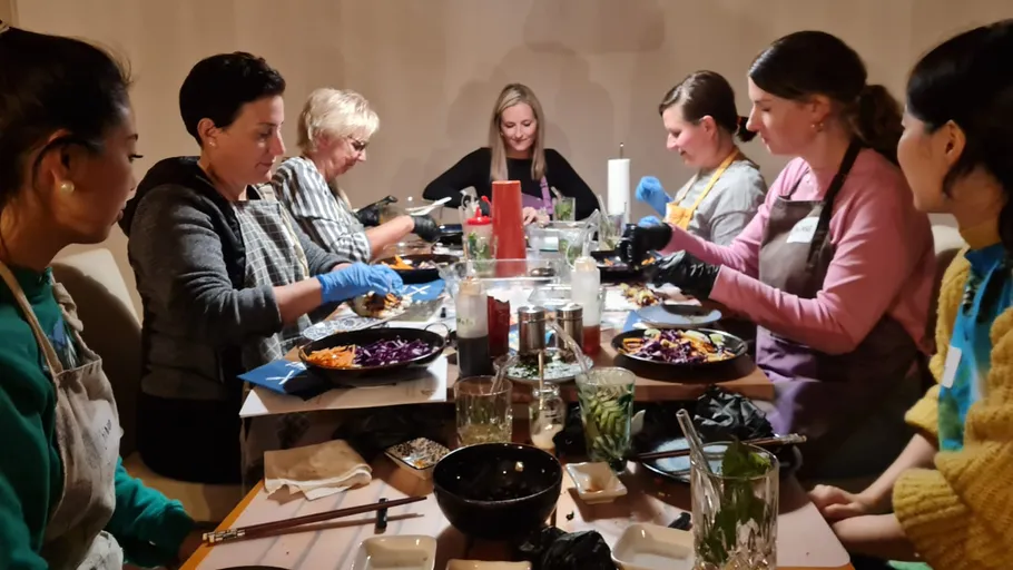 People prepare food at a dining table.